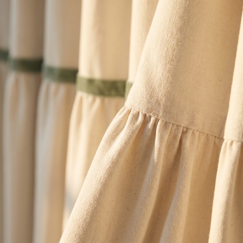 Close detail of ivory sailcloth drapery folds with a sage-green trim