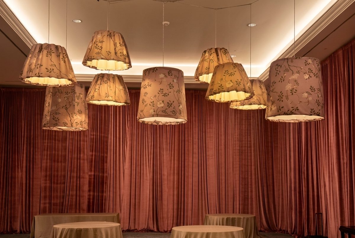 Custom chinoiserie floral drum-shade pendants glowing over dusty-rose velvet drapery
