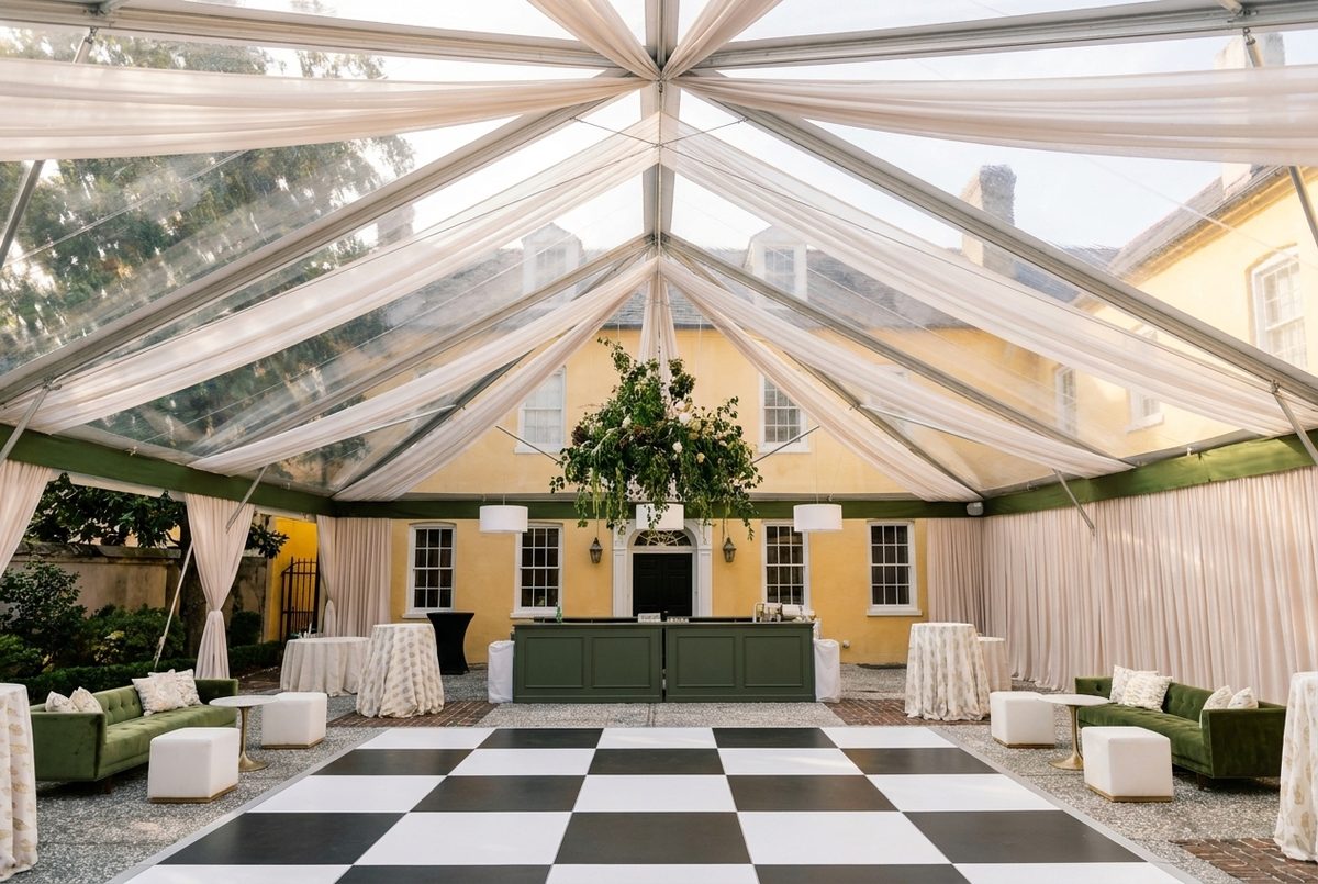 Clear-top tent at a historic Charleston home with green velvet lounges and suspended greenery