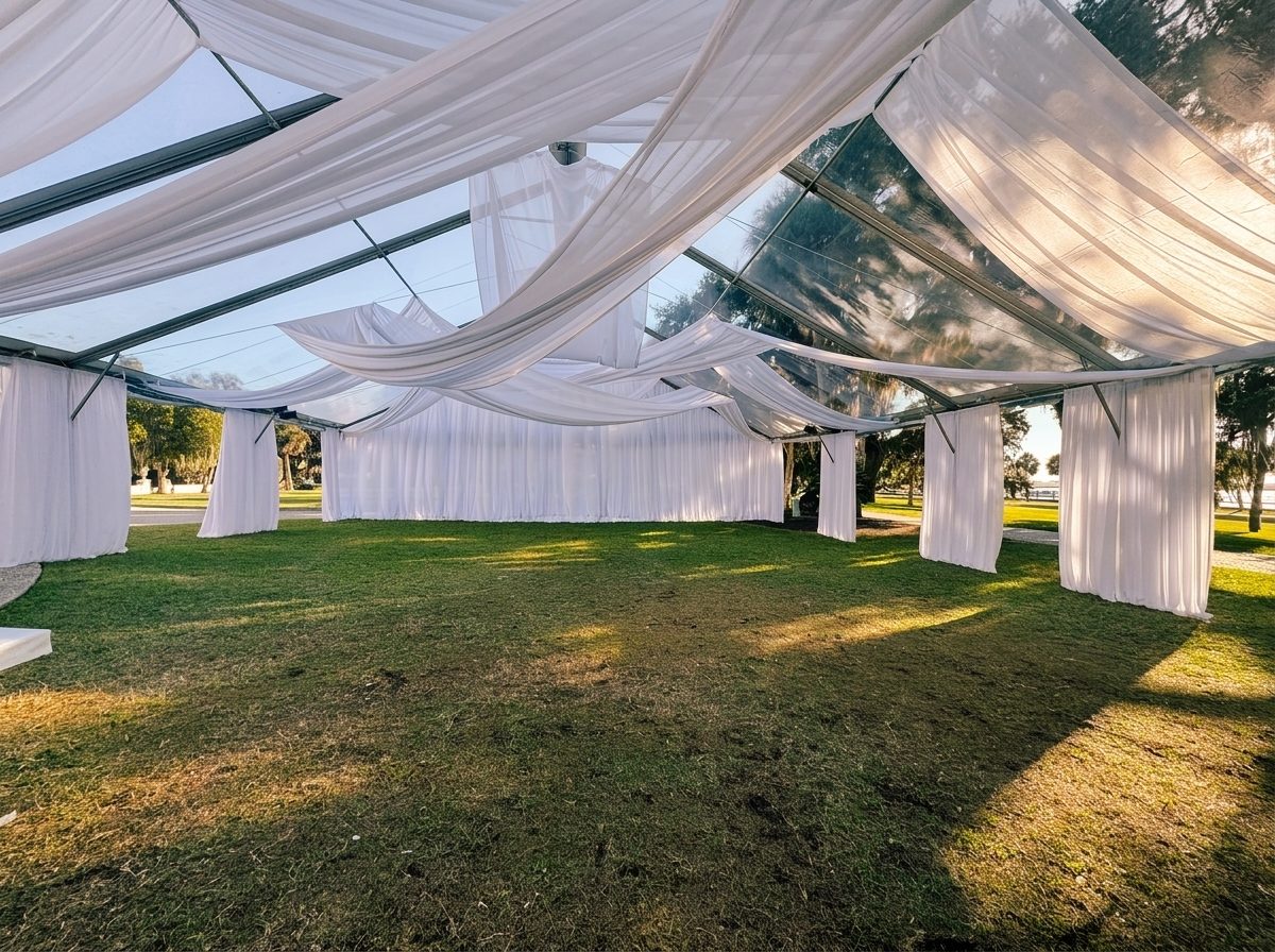 Clear-top event tent with flowing white fabric draping over a green Lowcountry lawn