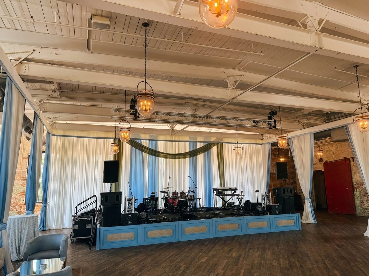 Custom event stage with ivory and dusty-blue draping and professional rigging